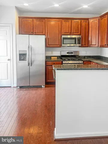 a kitchen with granite countertop a refrigerator and a stove top oven
