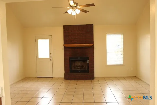 a view of an empty room with a fireplace and a window