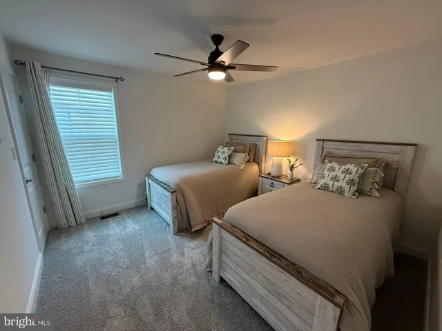 a bedroom with two beds and ceiling fan
