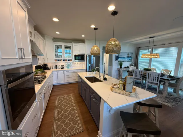 a large kitchen with stainless steel appliances granite countertop a stove a sink dishwasher a dining table and chairs with wooden floor