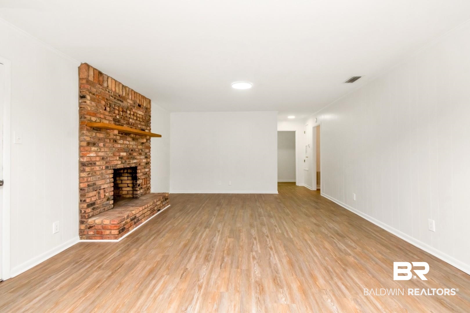 5217 Perin Road Mobile, AL 36693 - Photo 23 of 45 Brick fireplace with a wood mantel, wood-finish flooring, white walls, and a recessed ceiling light