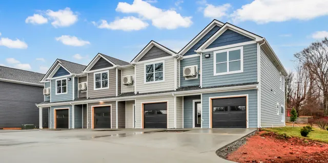 a front view of a house with yard and parking
