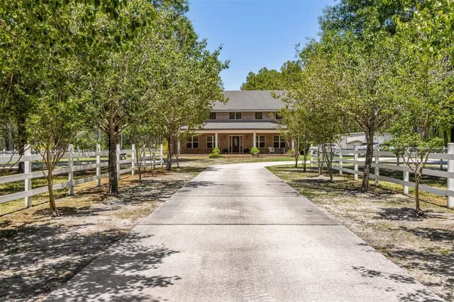 a view of a house with large trees and park