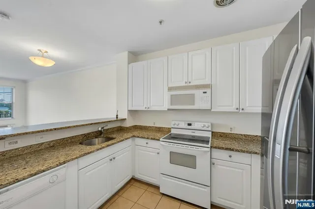 a kitchen with granite countertop white cabinets and white appliances