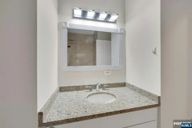 a bathroom with a granite countertop sink and a mirror
