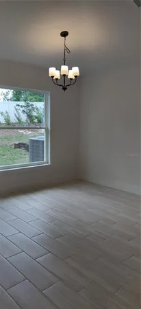 an empty room with wooden floor chandelier and windows