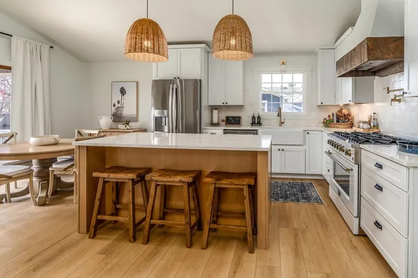 a kitchen with stainless steel appliances a table chairs refrigerator and cabinets