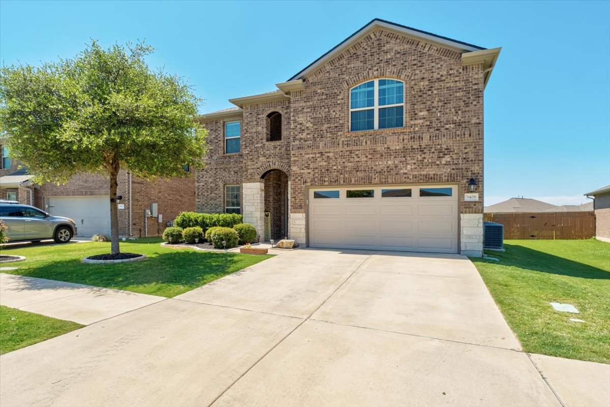 5408 Vanner Path Georgetown, TX 78626 - Photo 2 of 34 Brick facade residential structure featuring an integrated two-car garage, arched entry, and manicured landscaping