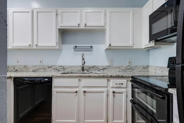 a kitchen with granite countertop white cabinets and a sink