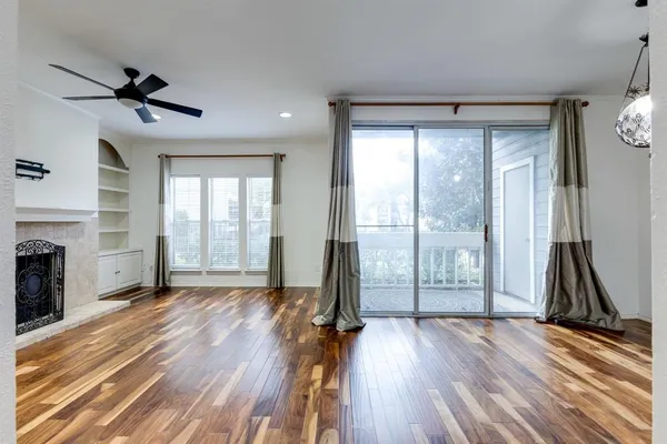 a view of a livingroom with wooden floor a fireplace and windows