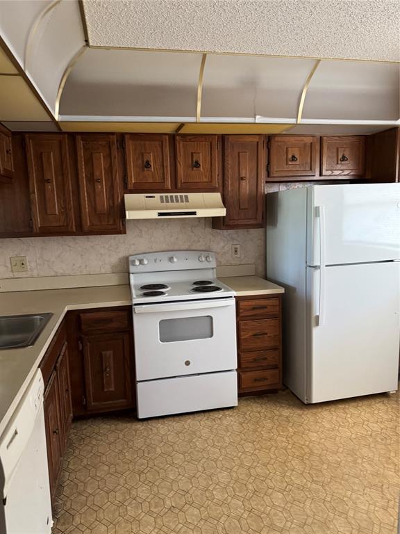 a kitchen with stainless steel appliances granite countertop a refrigerator a stove and a sink