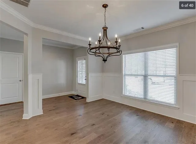 a view of a room with wooden floor chandelier and windows