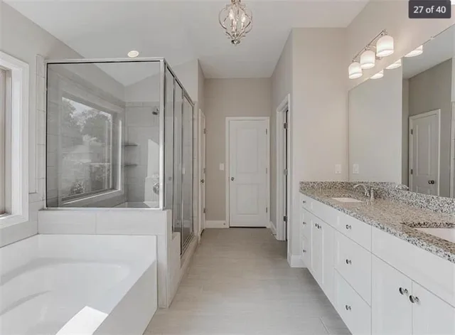 a bathroom with a granite countertop sink a mirror a bathtub and shower