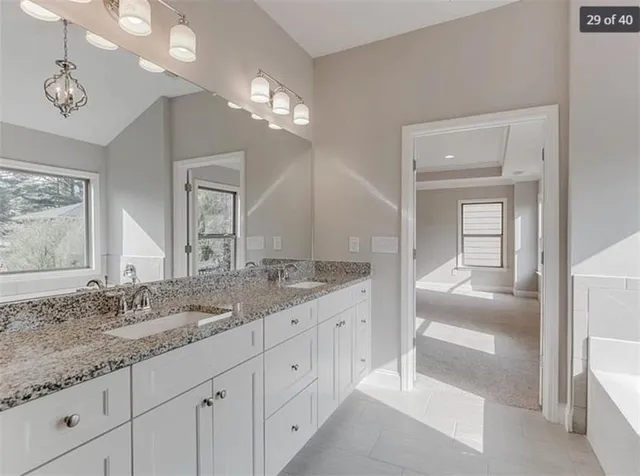 a spacious bathroom with a granite countertop sink a mirror and a shower