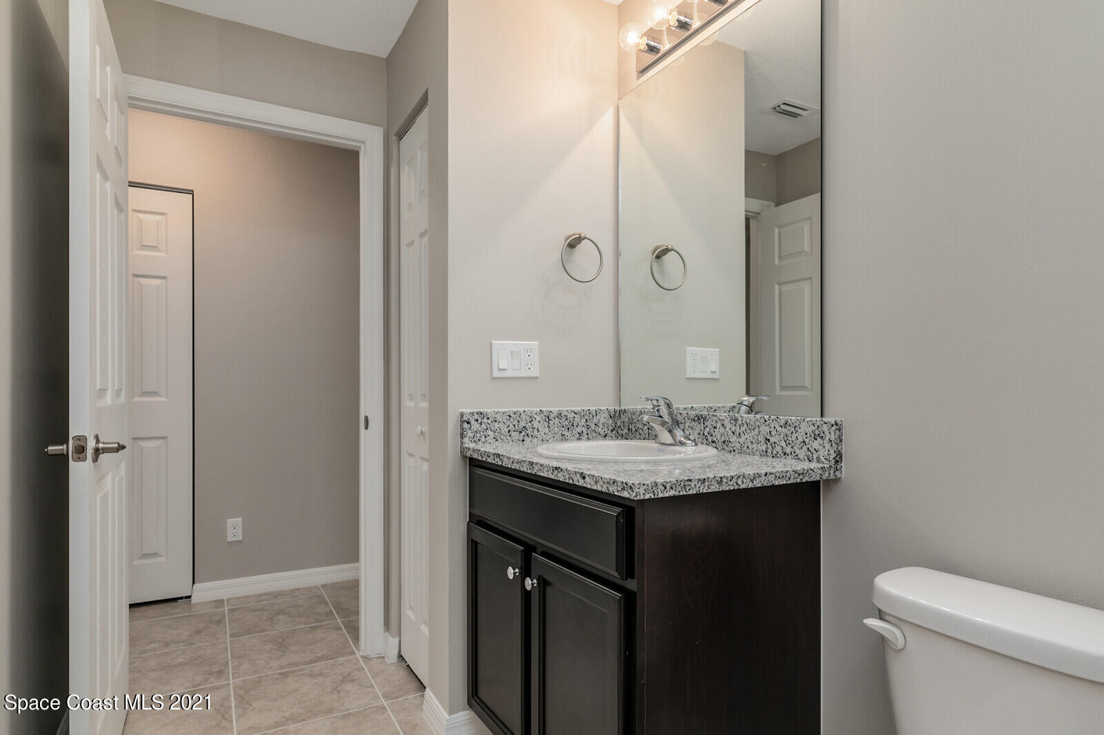 428 Scarlet Road Southwest Palm Bay, FL 32908 - Photo 22 of 35 a bathroom with a granite countertop sink a toilet and a mirror