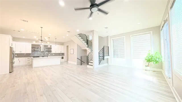 a large white kitchen with granite countertop a stove a sink and a large window
