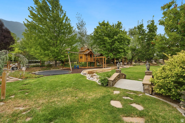 672 Perry Hollow Drive Mapleton, UT 84664 - Photo 95 of 106 Expansive backyard featuring a stone bridge with decorative lanterns, mature trees, and a built-in play structure