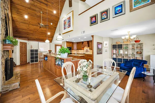 a living room with a dining table chairs wooden floor and a ceiling fan