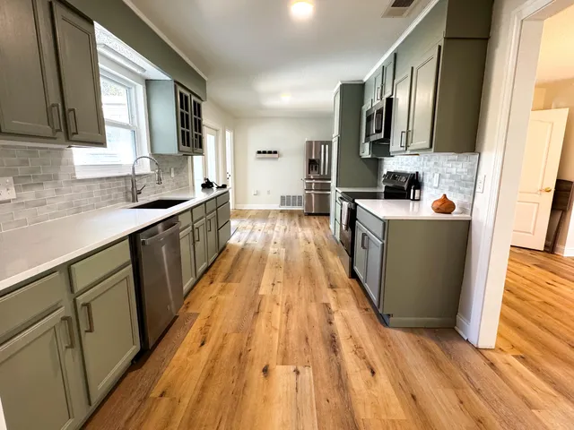 a kitchen with stainless steel appliances a sink dishwasher stove and wooden floor