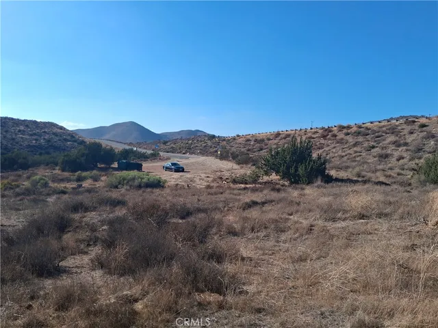 a view of a dry field with mountains in the background