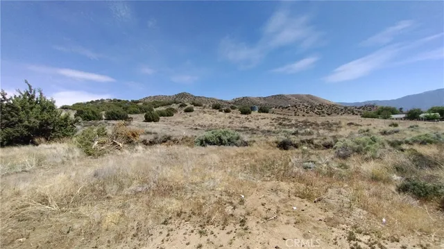 a view of a dry yard with mountains in the background