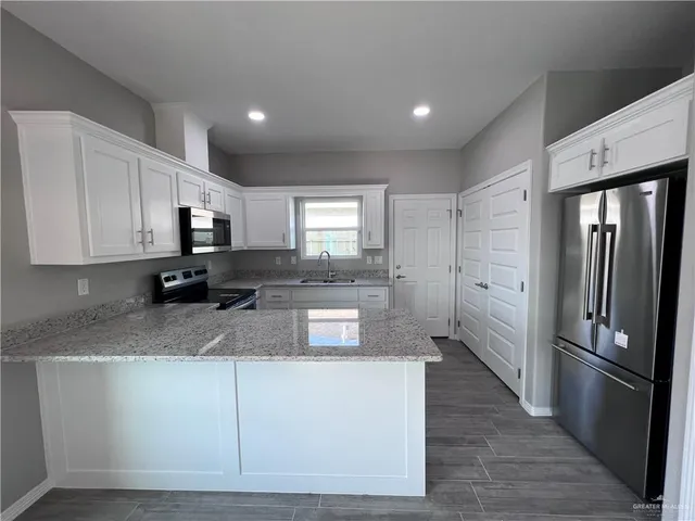 a kitchen with stainless steel appliances granite countertop a refrigerator a stove a sink and a microwave