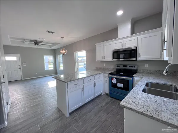a kitchen with stainless steel appliances kitchen island granite countertop a stove a sink and a microwave