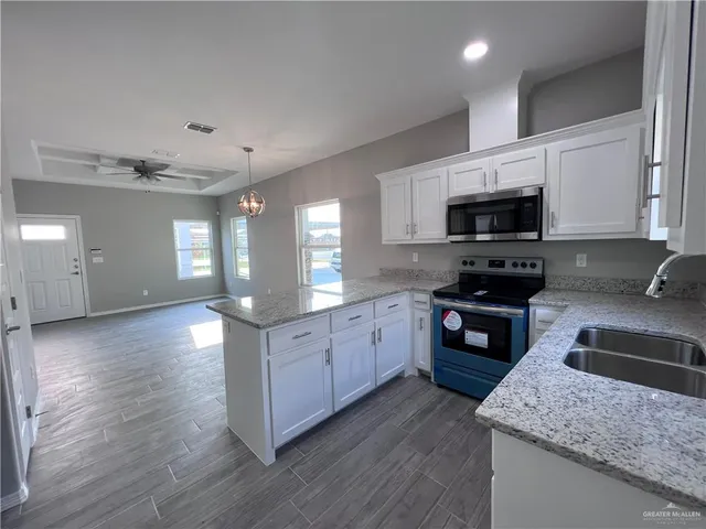 a kitchen with stainless steel appliances kitchen island granite countertop a stove a sink and a microwave