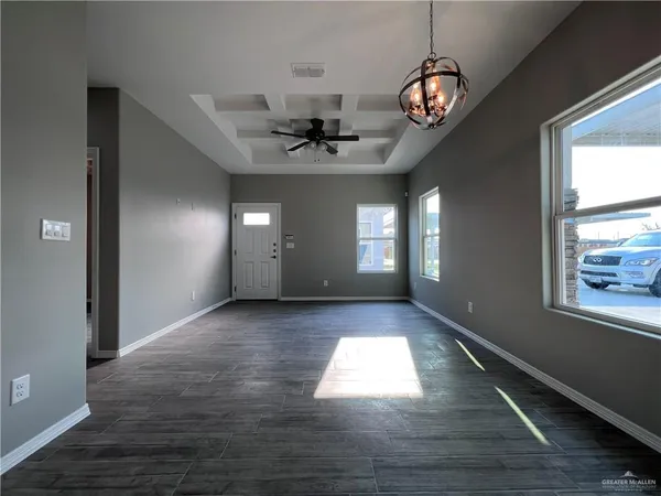 a view of an empty room with window and wooden floor
