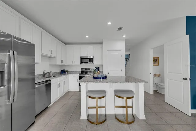 a kitchen with stainless steel appliances granite countertop a sink a stove a refrigerator cabinets and chairs