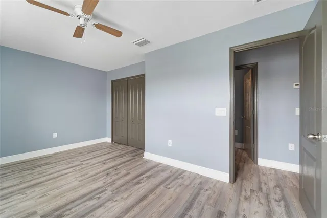 a view of empty room with wooden floor and fan