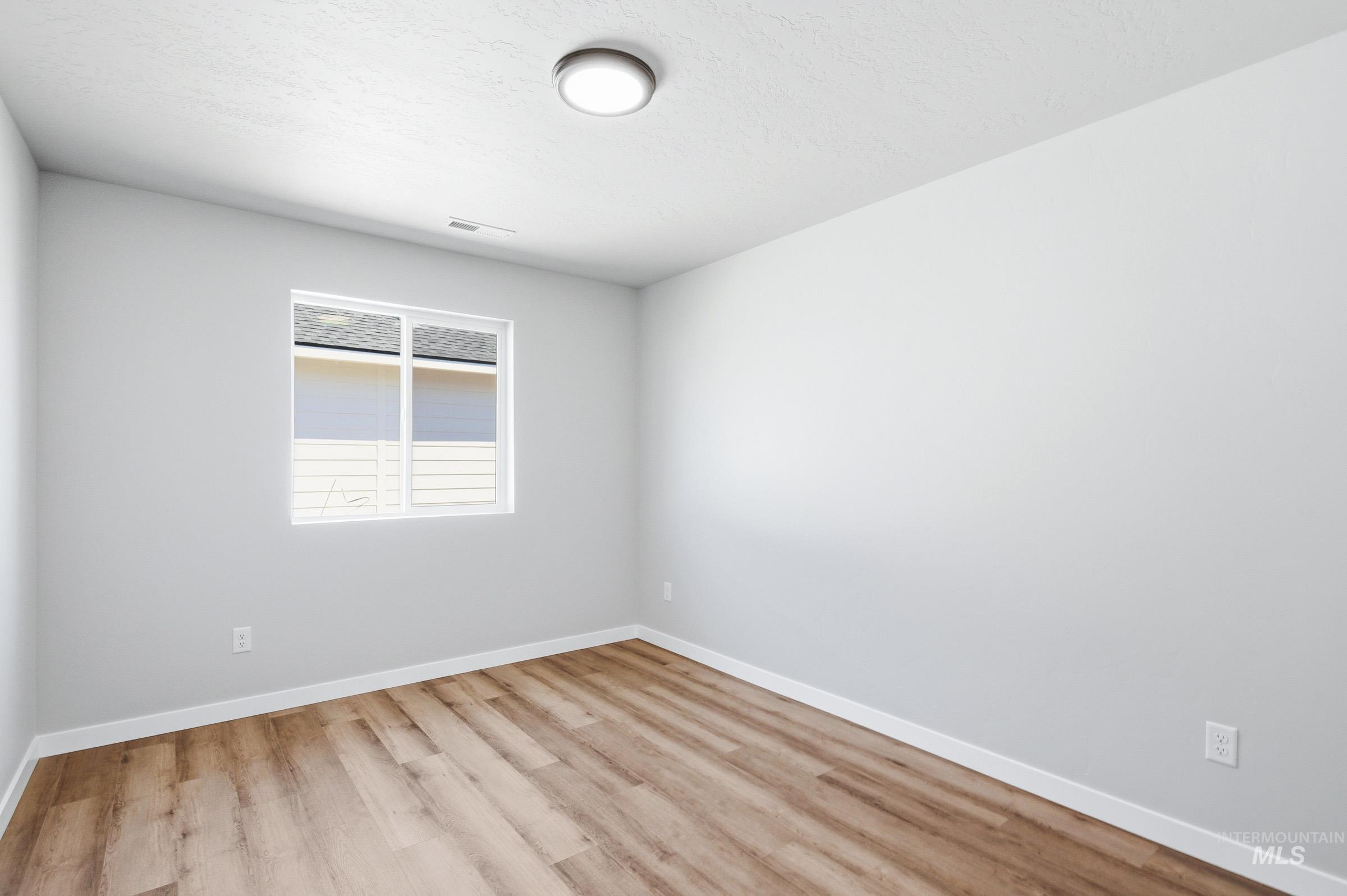 12805 Decatur Street Nampa, ID 83651 - Photo 16 of 20 Bright interior space featuring wood-finish flooring, white baseboards, and a single window with white trim