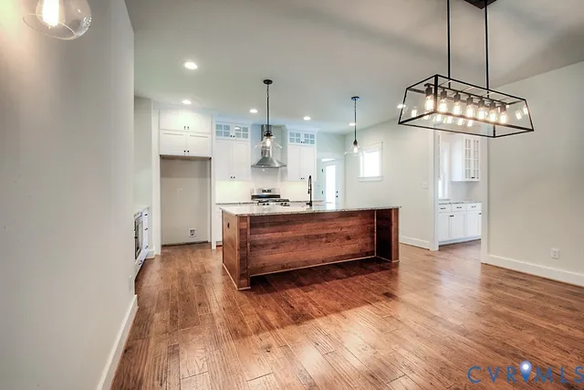 a dining hall with wooden floor and a kitchen view