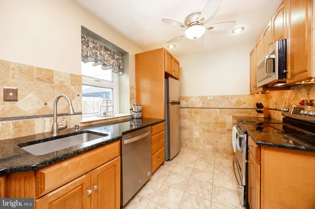 a kitchen with stainless steel appliances granite countertop a sink a stove and a refrigerator