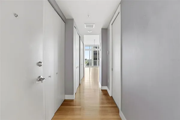 a view of a hallway with wooden floor and a bathroom