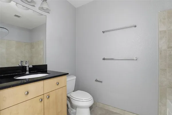 a bathroom with a granite countertop sink a toilet and a mirror