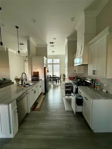 a kitchen with stainless steel appliances granite countertop wooden cabinets a sink dishwasher a stove and a refrigerator