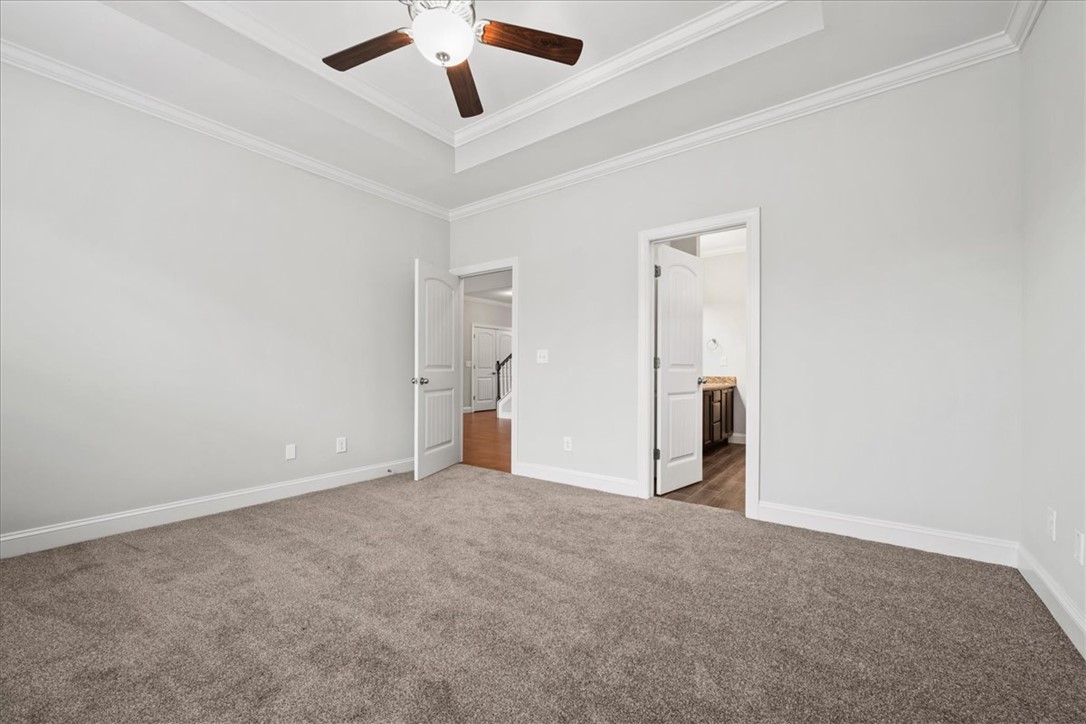 102 Ripplestone Way Anderson, SC 29621 - Photo 20 of 39 A spacious sleeping area showcasing a tray ceiling, crown molding, and plush carpeting for comfort.