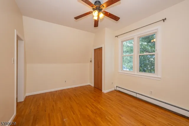 a view of empty room with wooden floor and fan