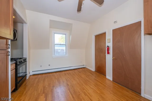 an empty room with wooden floor cabinet and windows