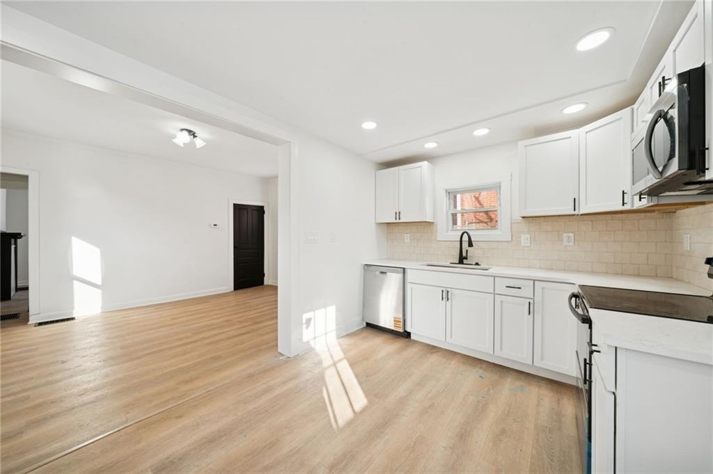 216 Whipple Street Pittsburgh, PA 15218 - Photo 4 of 29 a kitchen with granite countertop a stove top oven a sink dishwasher and a refrigerator with wooden floor