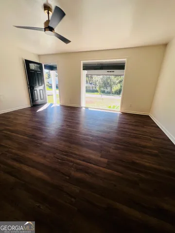 a view of an empty room with a window and wooden floor