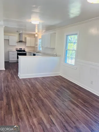 a room with wooden floors and kitchen view