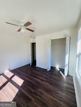 a view of empty room with wooden floor and fan
