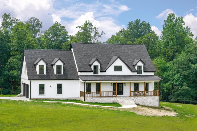 a front view of a house with a garden and trees