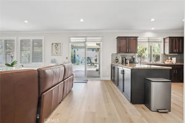 a kitchen with stainless steel appliances granite countertop a stove a sink dishwasher a refrigerator and a dining table with wooden floor