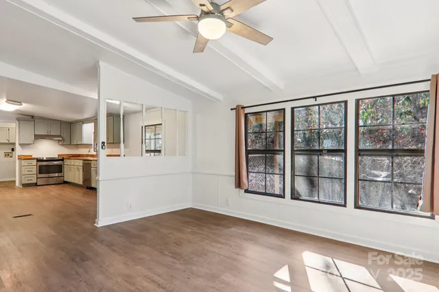 a view of an empty room with a window and wooden floor