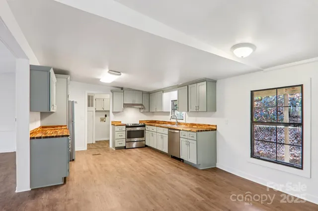 a large kitchen with stainless steel appliances granite countertop a stove top oven a sink dishwasher and a refrigerator with wooden cabinets