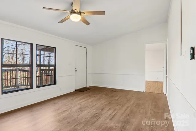 an empty room with windows and ceiling fan