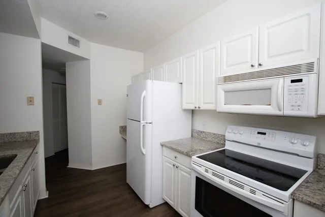 a kitchen with a refrigerator a stove and wooden floor